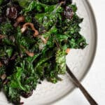 braised kale with cherries on a white plate