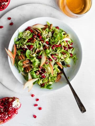 Brussels Sprout Slaw in White Bowl Garnished with Pomegranates
