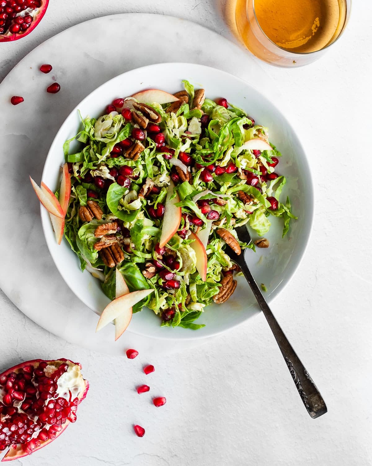 Brussels Sprout Slaw in White Bowl Garnished with Pomegranates