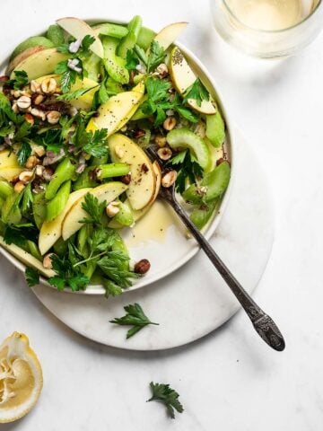 Celery salad with apples, shallots, parsley and walnuts on a flat plate