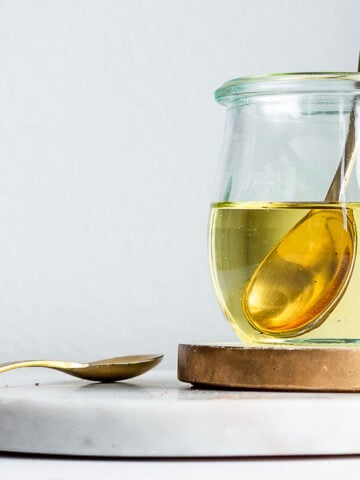 cod liver oil in a glass jar with a brass spoon