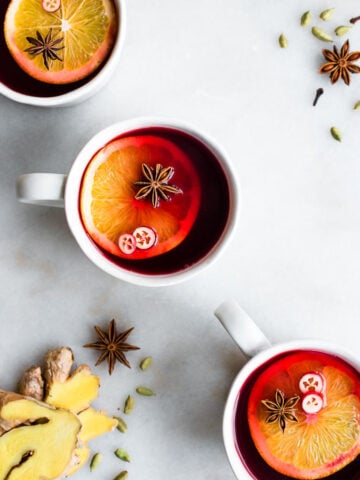 cranberry cider with orange slivers in 3 mugs