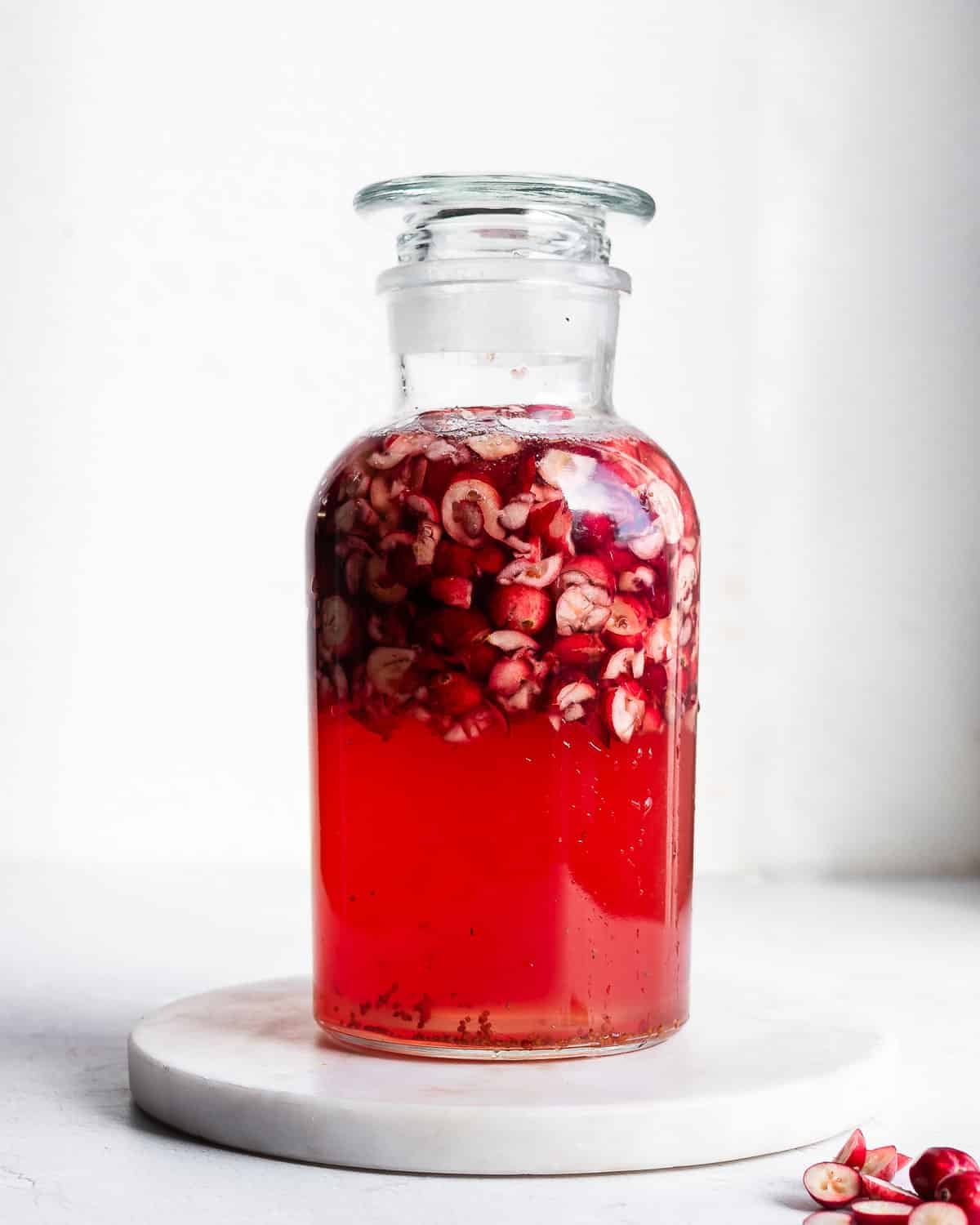 cranberry kvass fermenting in an apothecary jar