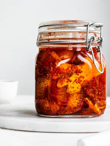 Daikon radish kimchi in a Fido jar on a marble serving tray