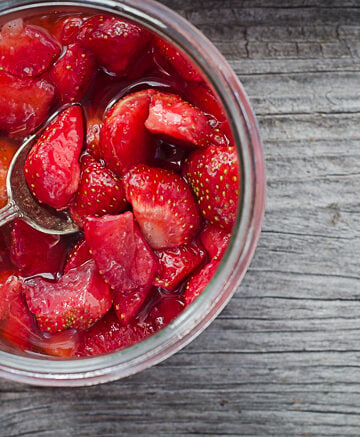 macerated strawberries in glass bowl on wooden surface