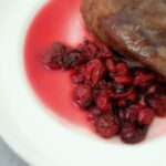 sour cherry sauce on a plate next to roasted duck