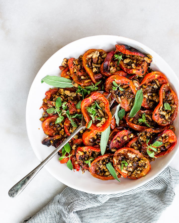 Roasted plum tomatoes with garlicky toasted pecan crumble in a white dish.