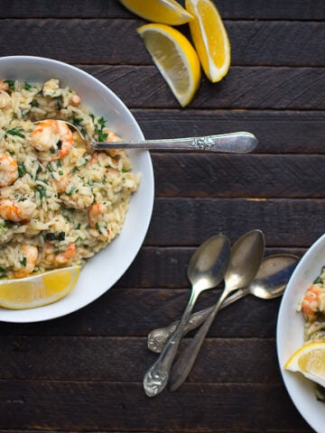 two dishes of shrimp risotto garnished with lemon and parsley