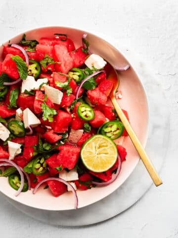 watermelon feta salad in a pink bowl with a gold spoon